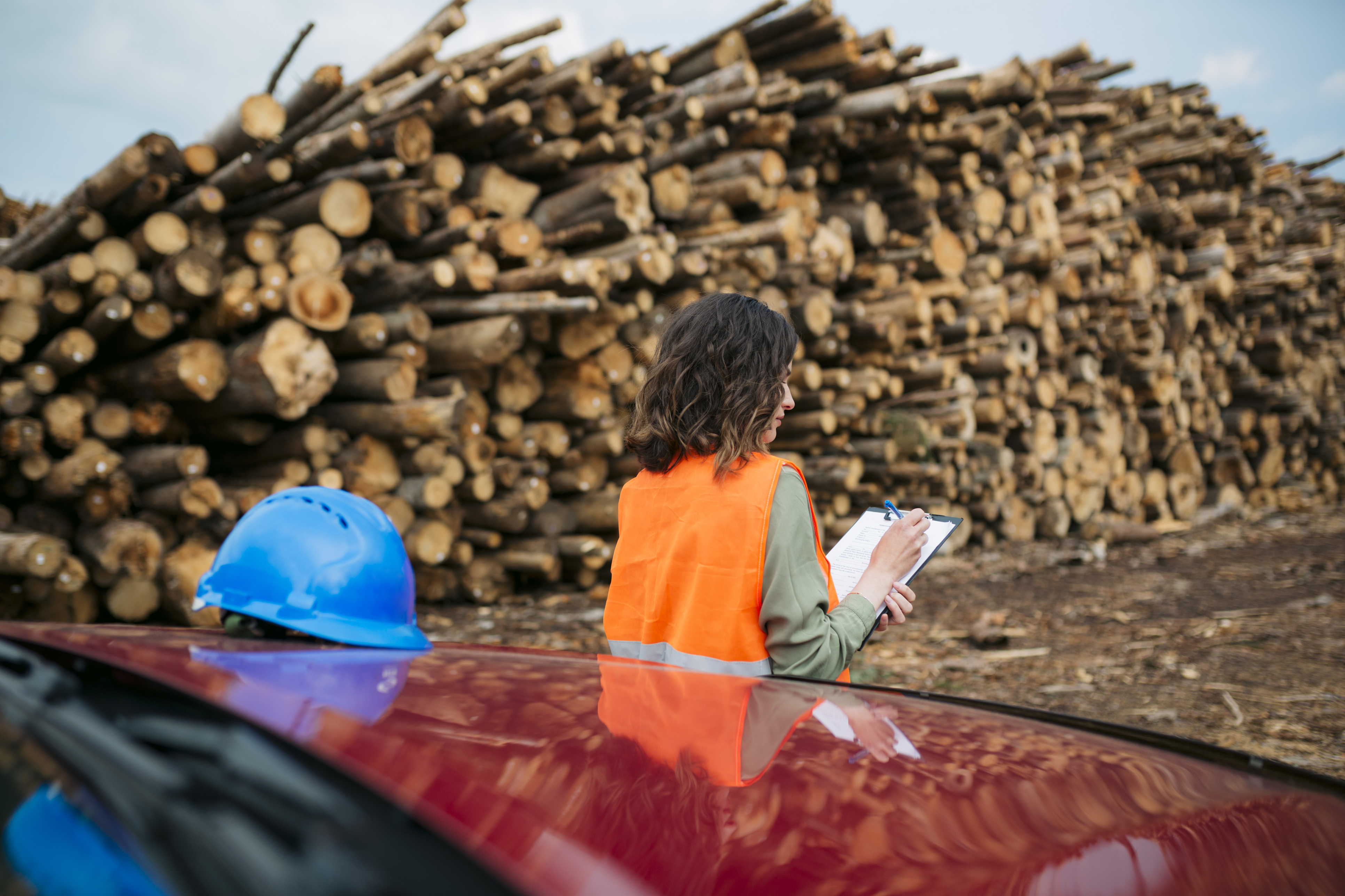 Woman worker working at a wood factory doing the inventory on the logs.